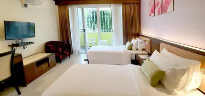 a hotel room with two beds and a television at The Mareeya Place in Kamala Beach