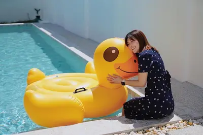 a woman hugging a large yellow rubber duck by a pool at BAANKAAN Pool Villa 1 in Ban Khlong Haeng
