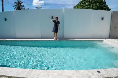 a woman standing in front of a swimming pool at BAANKAAN Pool Villa 1 in Ban Khlong Haeng