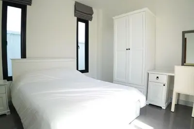 a white bedroom with a white bed and a mirror at BAANKAAN Pool Villa 1 in Ban Khlong Haeng