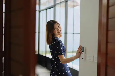 a woman in a polka dot dress unlocking a door at BAANKAAN Pool Villa 1 in Ban Khlong Haeng