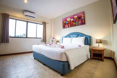 a bedroom with a large bed with a blue headboard at Rico's Patong Hotel in Patong Beach