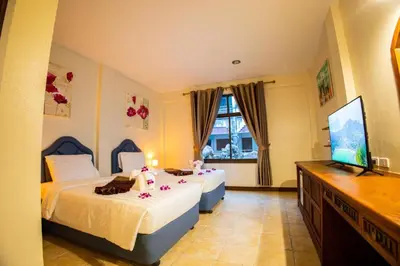 a bedroom with two beds and a flat screen tv at Rico's Patong Hotel in Patong Beach