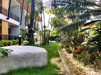 a garden with a large rock in front of a building at Phumi Resort in Thalang