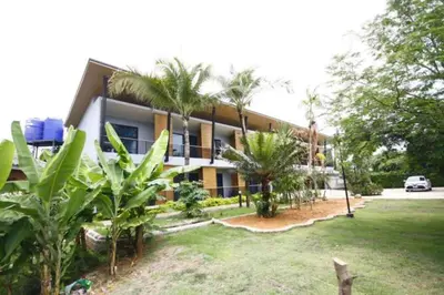 a building with palm trees in front of it at Phumi Resort in Thalang