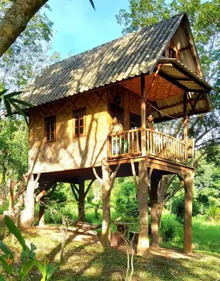 a tree house with people sitting on a deck at Treehouse Holidays-Family house in Ko Yao Noi