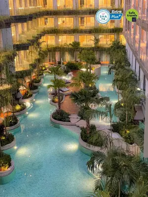 an indoor pool with palm trees in a building at Panwaburi Beachfront Resort - SHA Extra Plus in Panwa Beach
