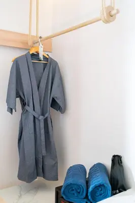a robe hanging on a rack next to blue towels at Panwaburi Beachfront Resort - SHA Extra Plus in Panwa Beach