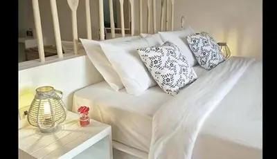 a white bed with pillows on it with a table at AT SEA Patong in Patong Beach