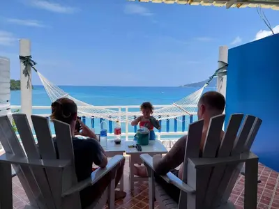 a group of people sitting around a table on a patio with the ocean at AT SEA Patong in Patong Beach