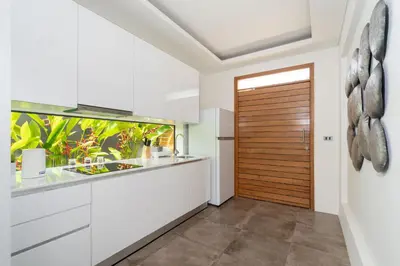 a kitchen with white cabinets and a wooden door at Blue Coral Luxury Villa - Tropical Modern Living in Phuket Town