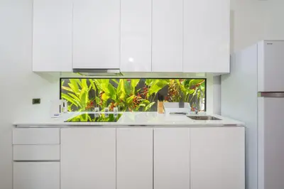 a white kitchen with plants in the background at Blue Coral Luxury Villa - Tropical Modern Living in Phuket Town