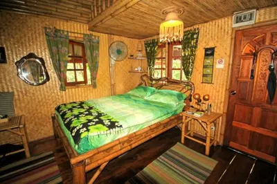 a bedroom with a bed and a table and a door at Treehouse Holidays-Garden View in Ko Yao Noi