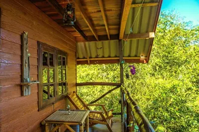 a porch of a house with a table and a bench at Treehouse Holidays-Garden View in Ko Yao Noi