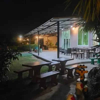 a group of picnic tables in front of a building at night at Davy Cottage Phuket in Thalang