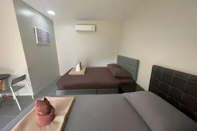 a small bedroom with two beds and a chair at Davy Cottage Phuket in Thalang