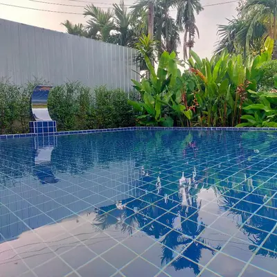 a swimming pool with blue tiles in the water at Davy Cottage Phuket in Thalang