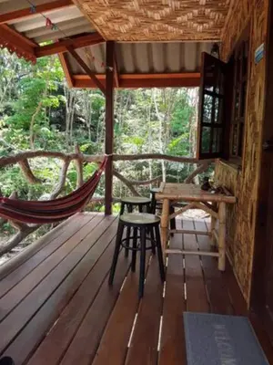 a hammock and a table on a porch of a cabin at Treehouse Holidays-Love Nest in Ko Yao Noi