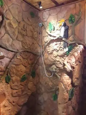 a bathroom with a rock wall with a bird on the wall at Treehouse Holidays-Love Nest in Ko Yao Noi