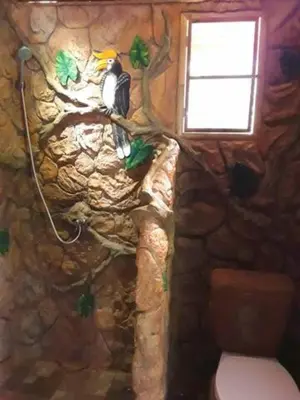 a bird sitting on a tree branch in a stone wall at Treehouse Holidays-Love Nest in Ko Yao Noi