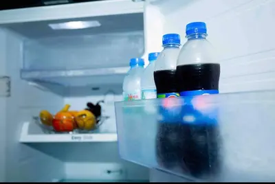 a refrigerator filled with bottles of soda and vegetables at The Deck Patong in Patong Beach