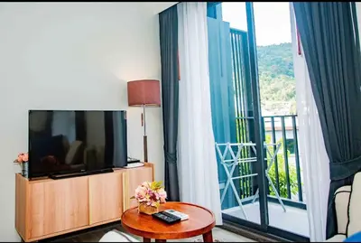 a living room with a flat screen tv and a balcony at The Deck Patong in Patong Beach
