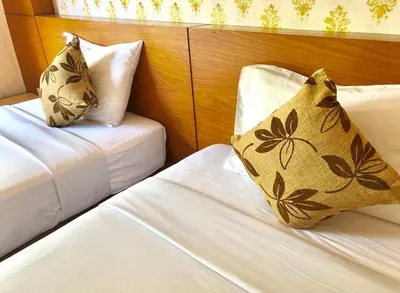 two beds in a hotel room with white sheets and pillows at Andaman Resort in Phi Phi Don