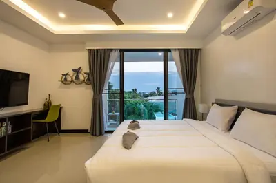 a bedroom with a large white bed and a balcony at Lovely pool villa 2 bedrooms in rawai with seaview in Ban Saiyuan (1)