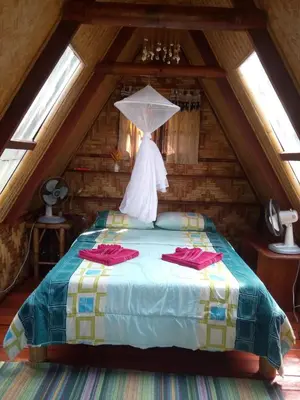 a bedroom with a bed with an umbrella in a attic at Treehouse Holidays-Little house in Ko Yao Noi