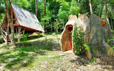 a log cabin with a rock and a house at Treehouse Holidays-Little house in Ko Yao Noi