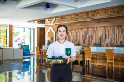 a woman holding a tray of food in a restaurant at Royal Yao Yai Island Beach Resort in Ko Yao Yai