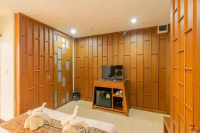 a room with wood paneled walls and a tv at Lotus Hotel Patong in Patong Beach