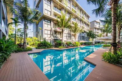 a swimming pool in front of a building with palm trees at Mountain View Apartment - Bangtao in Kathu