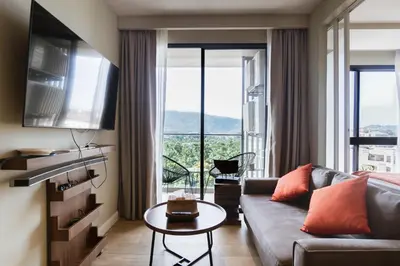 a living room with a couch and a large window at Mountain View Apartment - Bangtao in Kathu