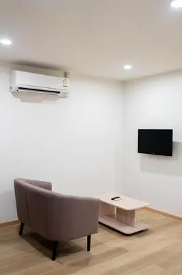a living room with a couch and a tv on a wall at CA Hotel and Residence Phuket - SHA Extra Plus in Phuket Town