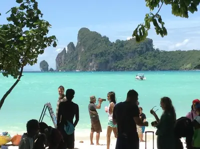a group of people standing on a beach with the ocean at Coco's Guest House in Phi Phi Don