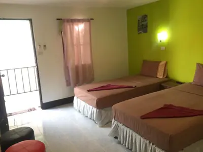 two beds in a room with green walls at Coco's Guest House in Phi Phi Don