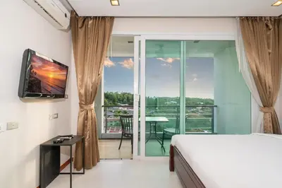 a bedroom with a bed and a television and a balcony at Sea and Sky Condominium by Lofty in Karon Beach