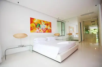 a white bedroom with a large bed and a painting at Siam Palm Residence in Patong Beach