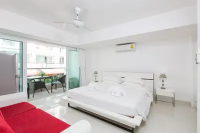 a white bedroom with a large bed and a red couch at Siam Palm Residence in Patong Beach