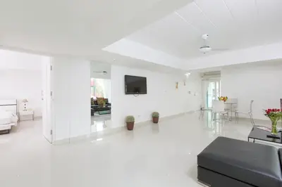a white living room with a couch and a tv at Siam Palm Residence in Patong Beach