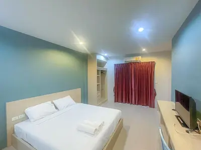a bedroom with a white bed and a red curtain at Hop On Phuket in Ban Bo Han