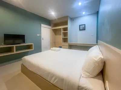 a bedroom with a large white bed and a tv at Hop On Phuket in Ban Bo Han