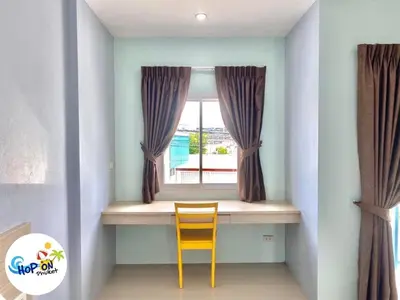 a yellow chair sitting in front of a window at Hop On Phuket in Ban Bo Han