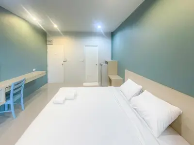 a bedroom with a large white bed and a blue wall at Hop On Phuket in Ban Bo Han