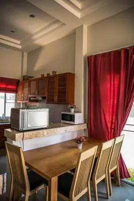 a kitchen with a wooden table and red curtains at Новый дом 106 м2, территория 160 м2 и своя парковка in Phuket Town