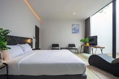 a bedroom with a large white bed and a tv at INNLUXPHUKET in Ban Laem Hin