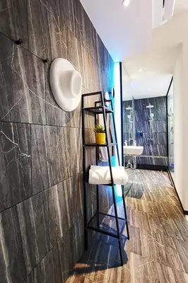 a bathroom with a wooden wall and a shelf with towels at INNLUXPHUKET in Ban Laem Hin