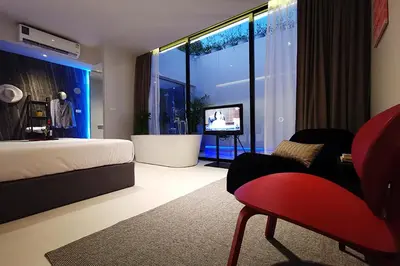 a bedroom with a bed and a large window with a television at INNLUXPHUKET in Ban Laem Hin