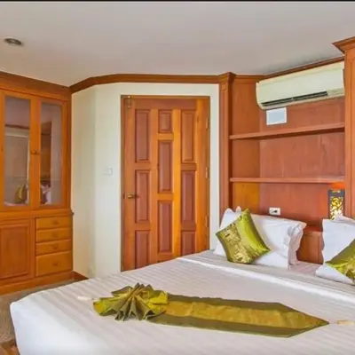 a bedroom with two beds and a wooden cabinet at Goodwill Beach House in Patong Beach